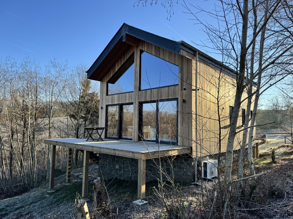 Houten Chalet Gedinne met grote ramen en een terras tussen de bomen